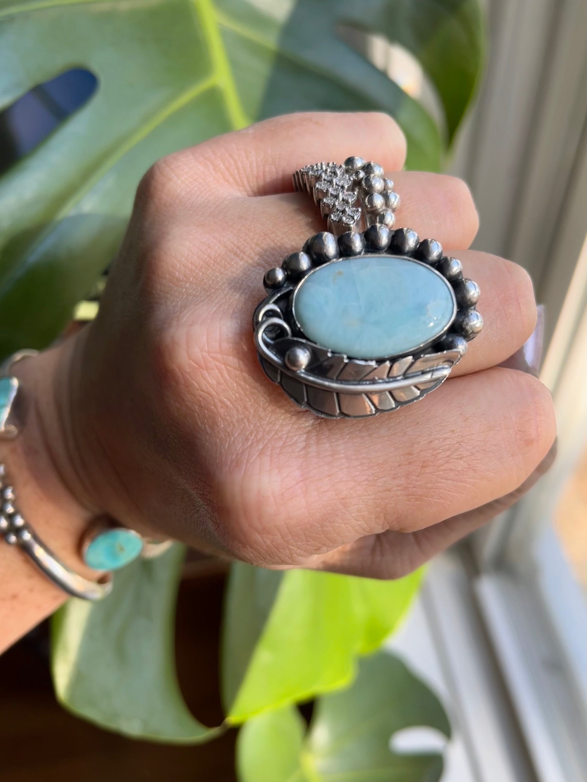 a large silver statement ring with Larimar on a hand