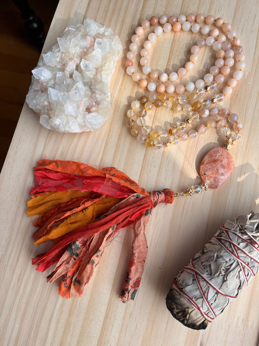 a peach and orange gemstone mala necklace with a cheery orange sari silk tassel 